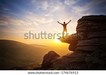 A person expressing freedom - reaching up into the sky against a sunset.