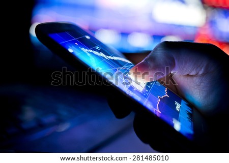 A city businessman using a mobile device to check stocks and market data. Close up shot.