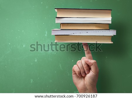 A student holding up study books with a single finger. Fast successful learning concept.