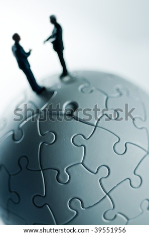 A macro shot of a globe puzzle with a couple of business people.