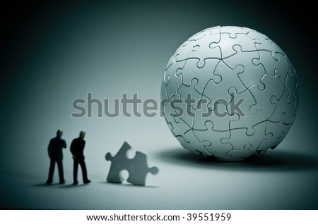 A macro shot of a globe puzzle with a couple of business people.