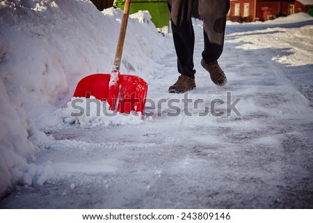 Man with snow shovel cleans sidewalks in winter. Winter time. Latvia. Europe.