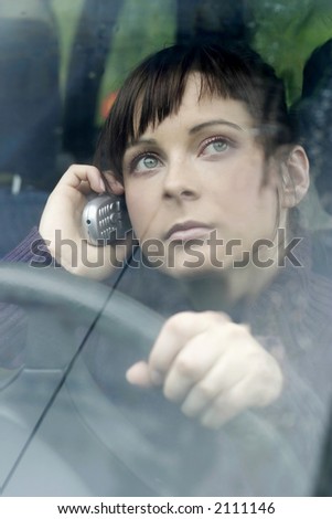portrait of a young woman, brunette in a car making a phonecall-close up