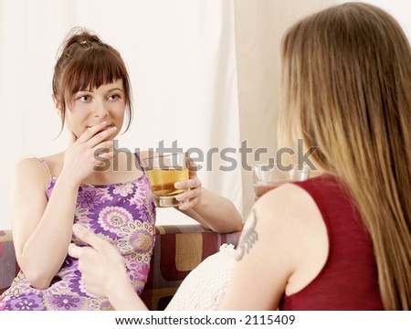 two girls, young women chatting on a sofa and drinking