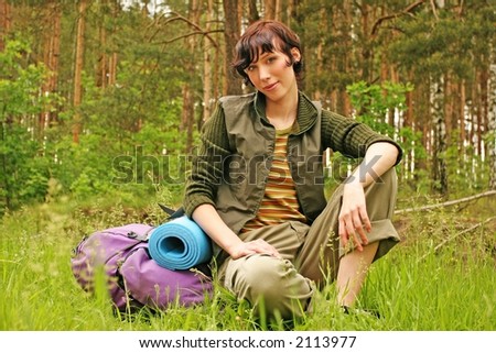 girl, young woman with a backpack hiking in a  forest-resting