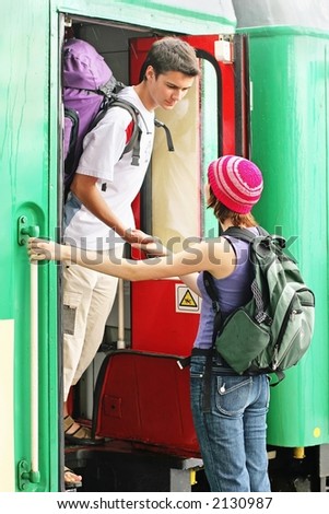 girl and a boy travelling with  backpacks-at a train station