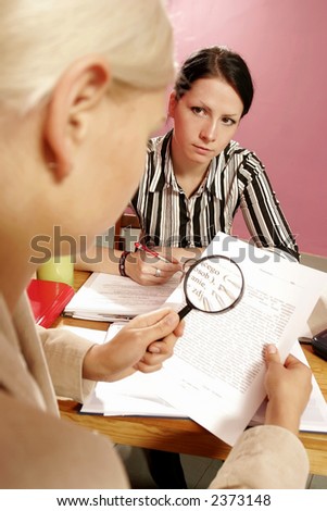 work environment- two women over some paperwork in modern office-on pink