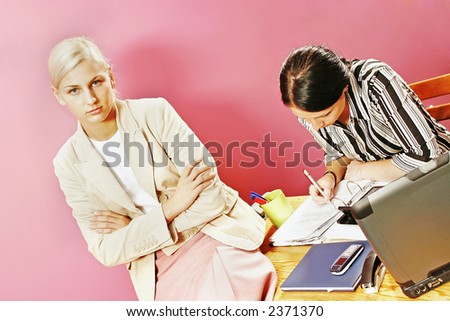 businesswoman and a secretary over some paperwork in modern office-on pink