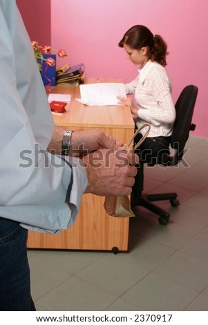 work environment- man bringing some gift for a woman working in a background