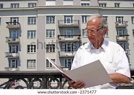 architect studying plans of house in front of appartment block