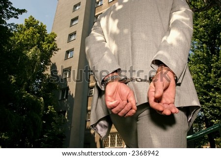 Arrested man in a business suit - hands in cuffs - close up