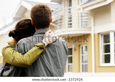 couple in  front of one-family house in modern residential area