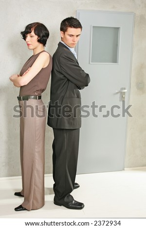 elegant, young couple standing back to back in a room