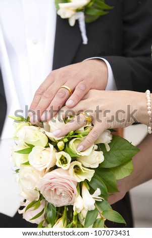 Newlywed couple holding hands on a bouquet