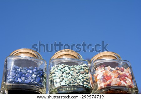 Pebble jewelry contained in three bottles under blue sky