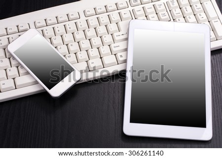 Tablet computer and smart phone on computer keyboard