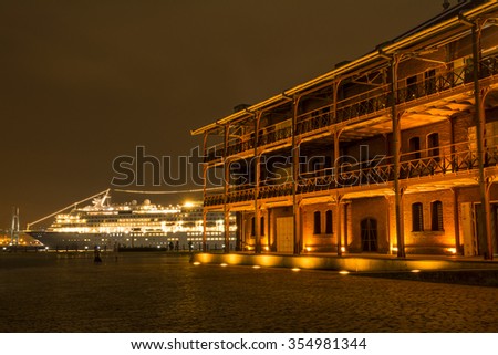 Light up old brick building in front of cruise ship in Yokohama at night