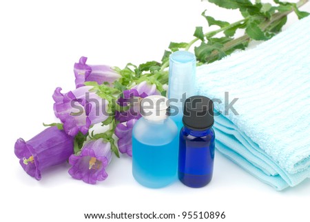 Essential oil and blue towel with Canterbury bells flower on white background