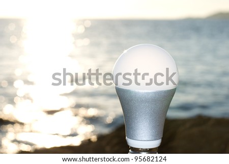 LED light bulb standing at the glitter seaside