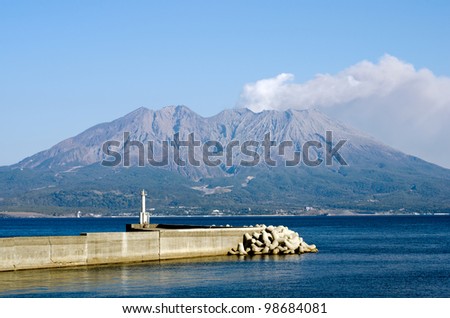 Active volcano and volcanic plume facing the sea with jetty