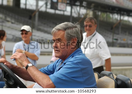 A picture of Al Unser driving a golf cart visiting old friends at Indianapolis