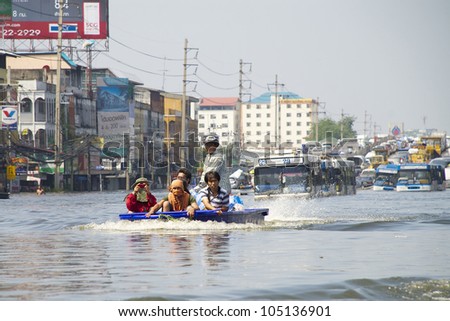 PATHUM THANI, THAILAND - OCT 27: Thai on a motor powered boat going through flood waters on a road in Pathum Thani, near Bangkok, Thailand on October 27, 2011.