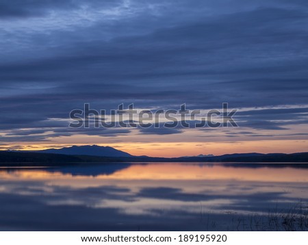 Beautiful orange sunset and clouds reflecting in a calm body of water-Morchua Lake