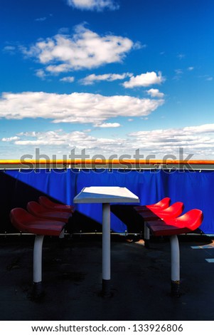 Red chairs on a blue background on the ferry in the spring