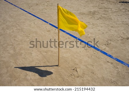 Yellow flag and the blue line on the golden sand beach