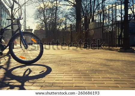 Bike with orange reflector at the fence of the park in the early spring on a sunny day