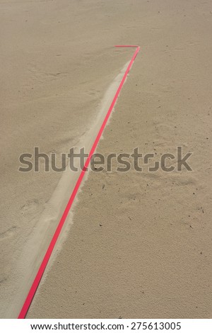 Detail of a red line in the sand volleyball court on the beach after the rain. Baltic sea