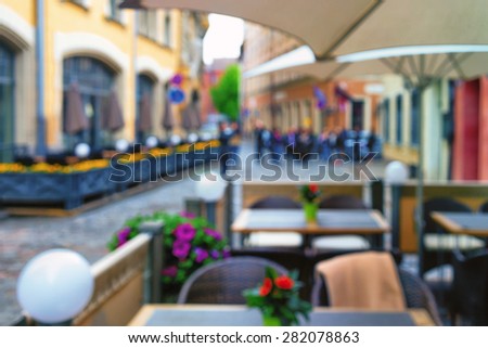 Outdoor cafe with beautiful flowers and umbrellas in the old town. Blurry
