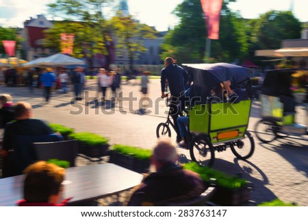 Trishaw rides fast on a green bike down the street of the old town in Europe