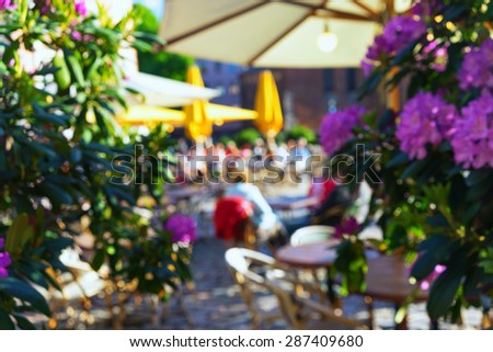 Outdoor cafe with beautiful flowers and umbrellas in the old town. Riga. Blurry