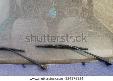 Windshield wipers on the windshield of a car under a layer of dust and air freshener in the cabin