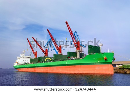 A ship with red and green stripes in the port of Riga for loading and unloading port cranes