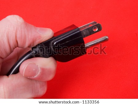 a hand holds out a plug over red