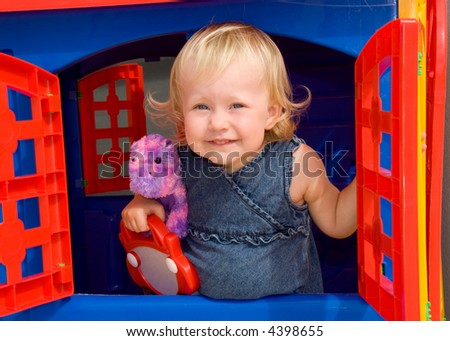 little girl peaks out the window of toy house