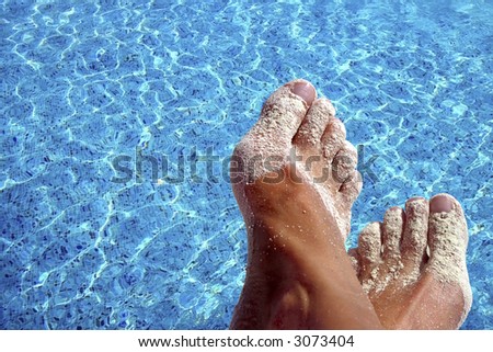 Sandy feet with blue pool water as background