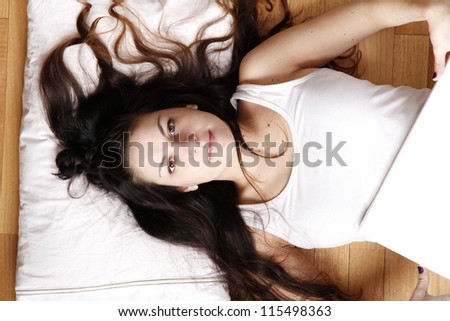 A young adult woman lying on the floor with a blank canvas.