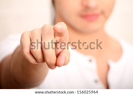 A young man pointing at you. Focus on Finger.