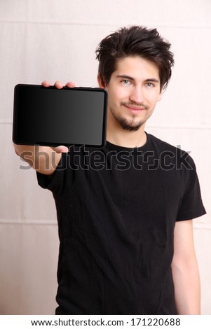 A young hispanic man holding a Tablet PC.