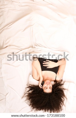 A young latin woman dreaming and sleeping while hugging herself.