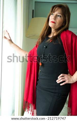 A melancholic beautiful mature woman looking out of the window.