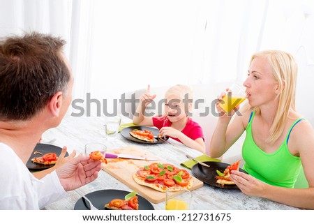 Father and mother with son and daughter eating Pizza for lunch or dinner.