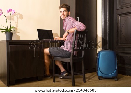 A young and handsome man using a laptop computer in a asian styled hotel room.