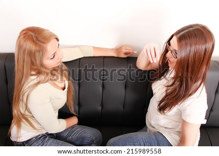 Two beautiful women chatting on the sofa at home.