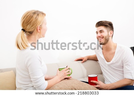 A young couple talking with coffee on the Sofa.