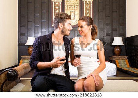 A young and happy couple enjoying a glass of wine in a asian style hotel room on their vacations.