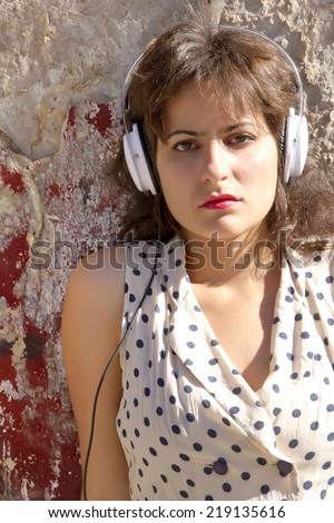 A vintage dressed girl listing to music in a urban environment.